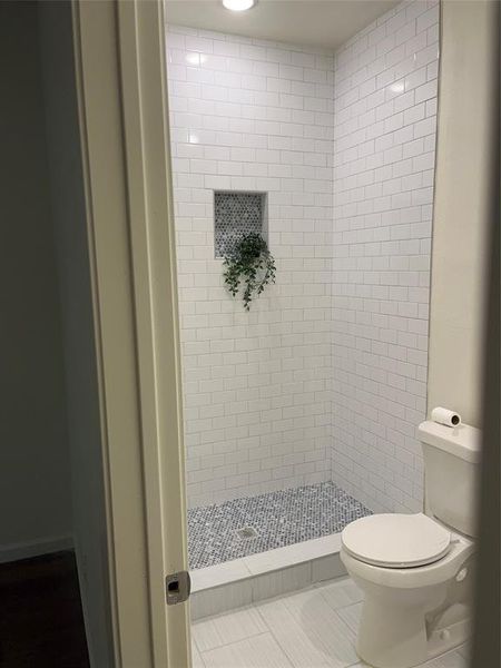 Contemporary shower with white subway tile surround, mosaic tile floor, recessed niche, and integrated ceiling light