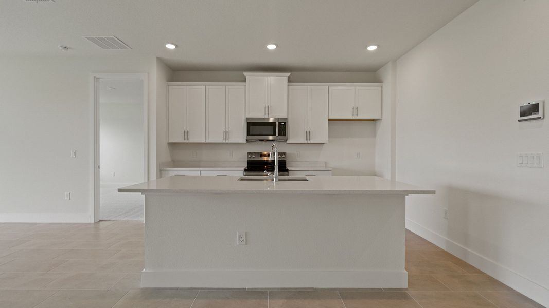 Kitchen and Island in the Buttonwood Floor Plan by DRB Homes in Ardisia Park in New Smyrna Beach