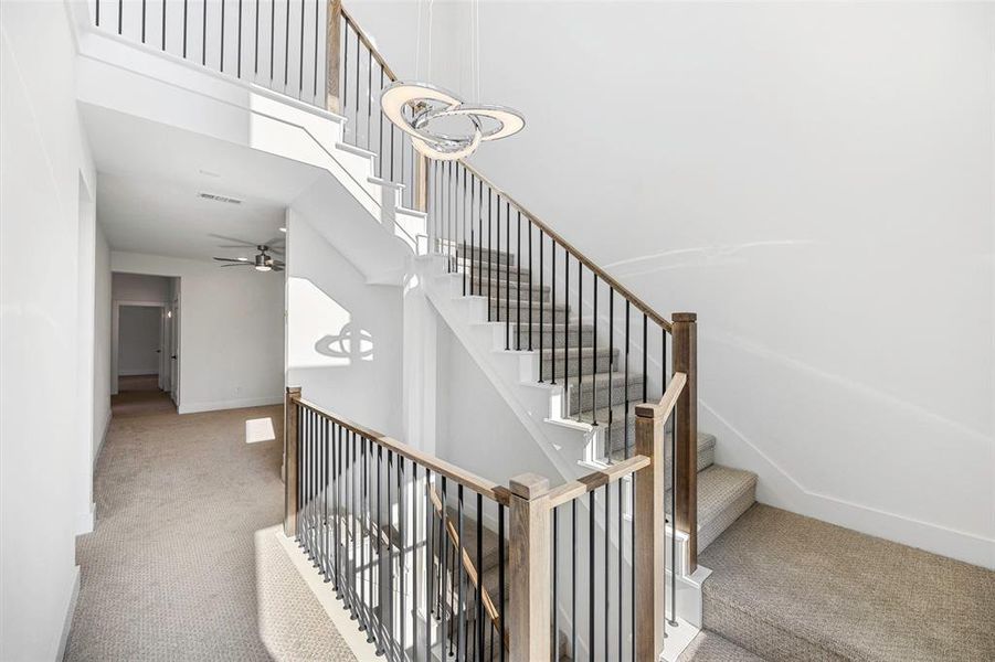 Stairs featuring carpet floors, visible vents, a towering ceiling, and baseboards