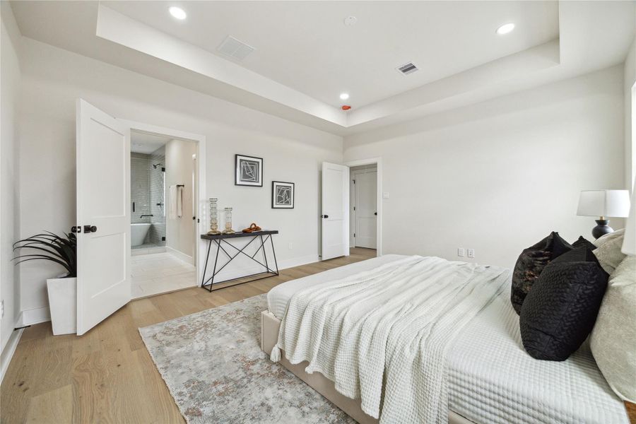 Experience luxury in this spacious primary bedroom, featuring a serene color palette, elegant tray ceiling, and an ensuite bathroom for ultimate comfort.