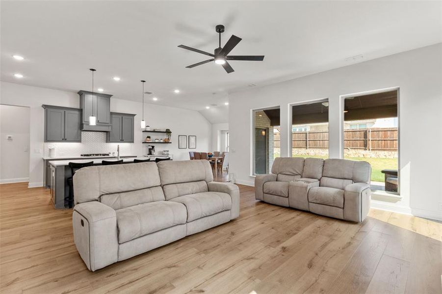 Living room featuring light wood finished floors, recessed lighting, a ceiling fan, and vaulted ceiling