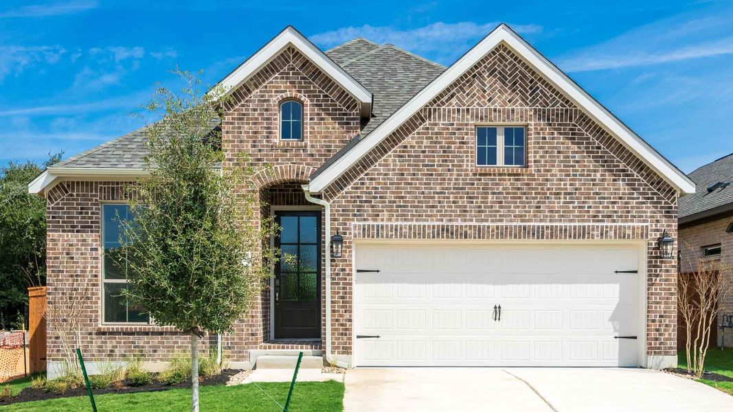 French country style house with brick siding, concrete driveway, a shingled roof, and a front yard