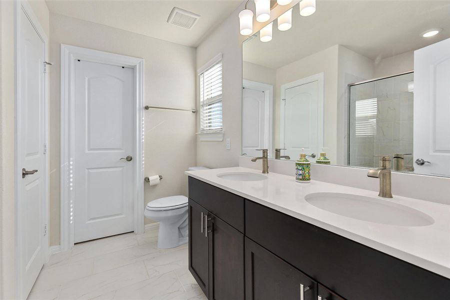 Bathroom with double vanity, a shower stall, light marble finish floors, and a closet
