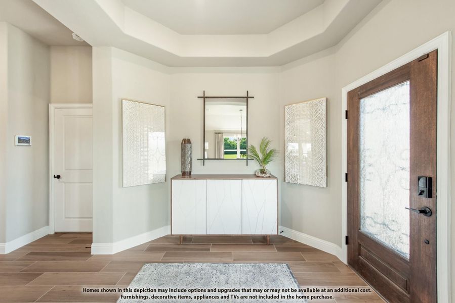 Entryway with tray ceiling, wood front door with glass panel, white console cabinet, and wood-look tile floors