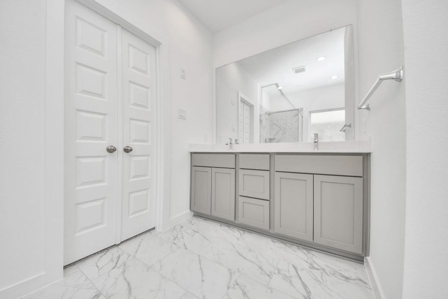 Elevate your daily routine at the elegant vanity, now equipped with double sinks, light countertops, modern hardware, and beautiful recessed lights. Sample photo of completed home with similar floor plan. Actual colors and selections may vary.