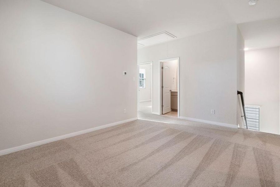 Empty room featuring attic access and light colored carpet