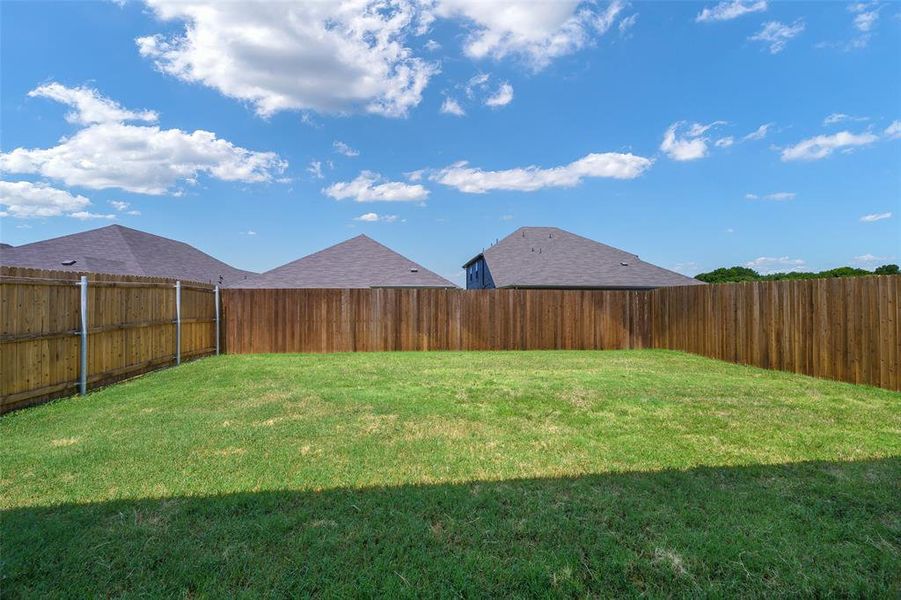Expansive backyard featuring a manicured lawn and tall wooden privacy fencing Expansive backyard featuring a manicured lawn and tall wooden privacy fencing