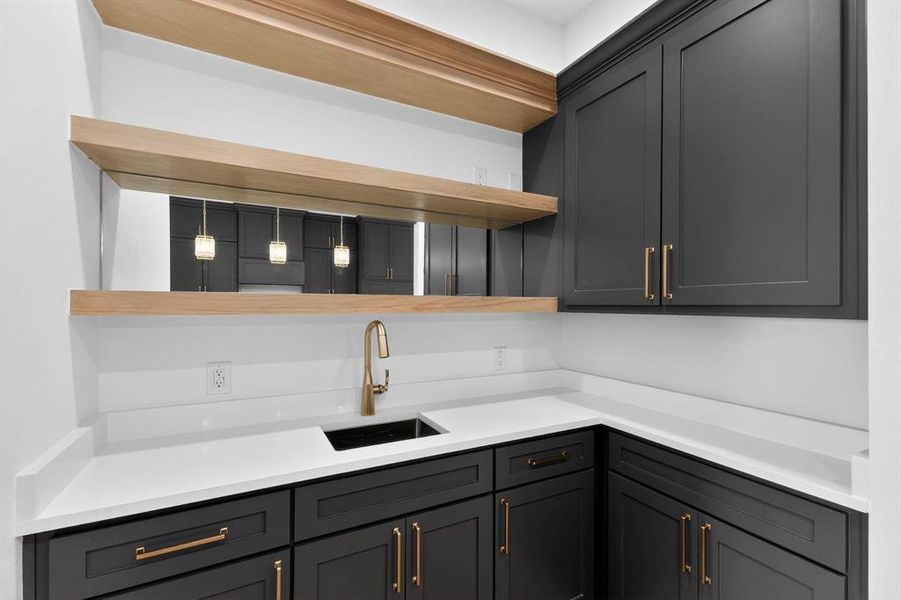 Kitchen featuring open shelves, gray cabinets, and light stone counters
