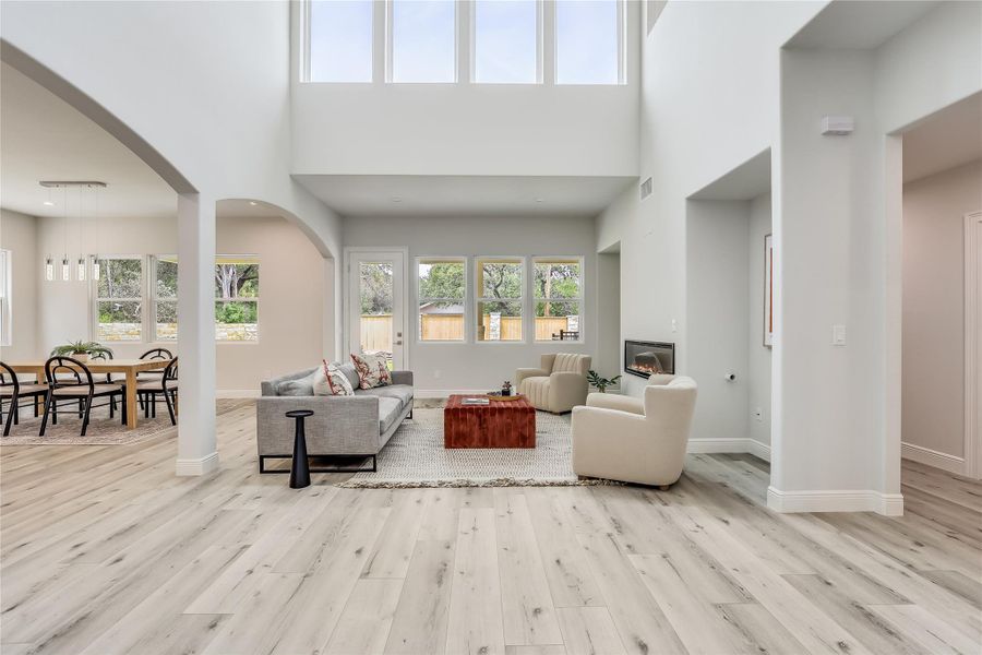 Living room featuring a wealth of natural light, light hardwood / wood-style floors, and a high ceiling