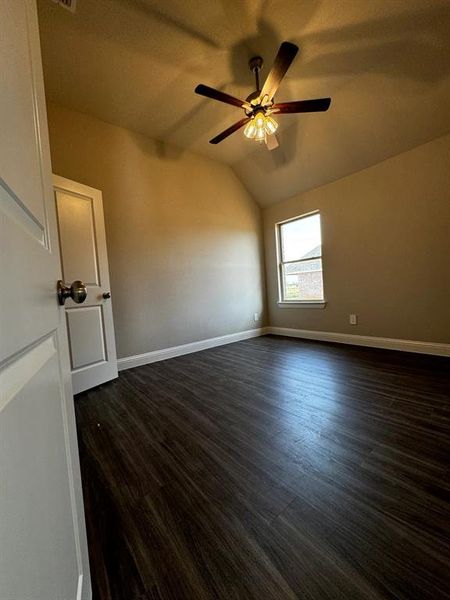 Empty room featuring ceiling fan, dark hardwood / wood-style flooring, and lofted ceiling