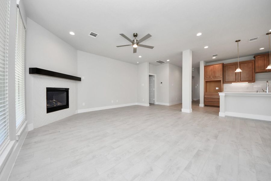 Relax and unwind in this inviting family room, illuminated by abundant natural light streaming in through tall windows, complemented by high ceilings and stunning flooring. Stay comfortable year-round with the gentle breeze from the ceiling fan, creating the perfect atmosphere for family gatherings.