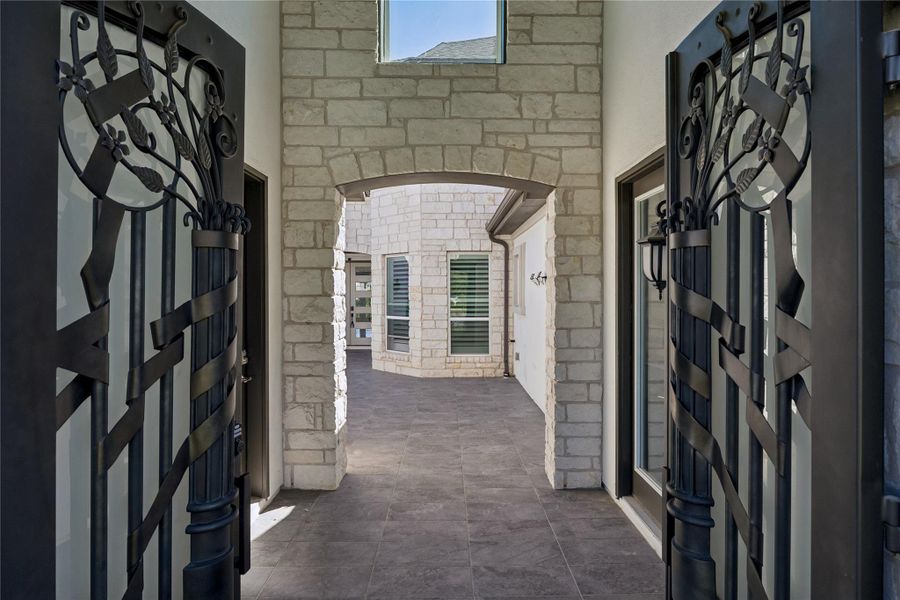 Ornate wrought iron gates welcome you into a tranquil, tiled courtyard framed by brick walls.