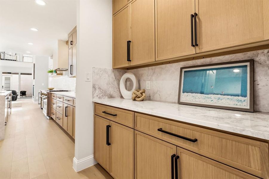 Kitchen featuring decorative backsplash, light stone countertops, stainless steel stove, light wood finish cabinetry, and recessed lighting