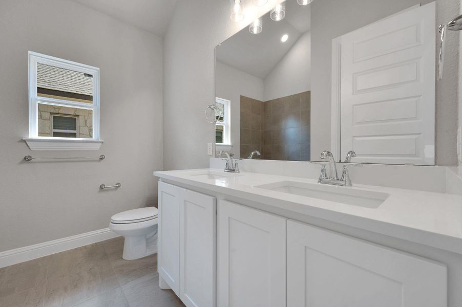 Full bath featuring double vanity and toilet