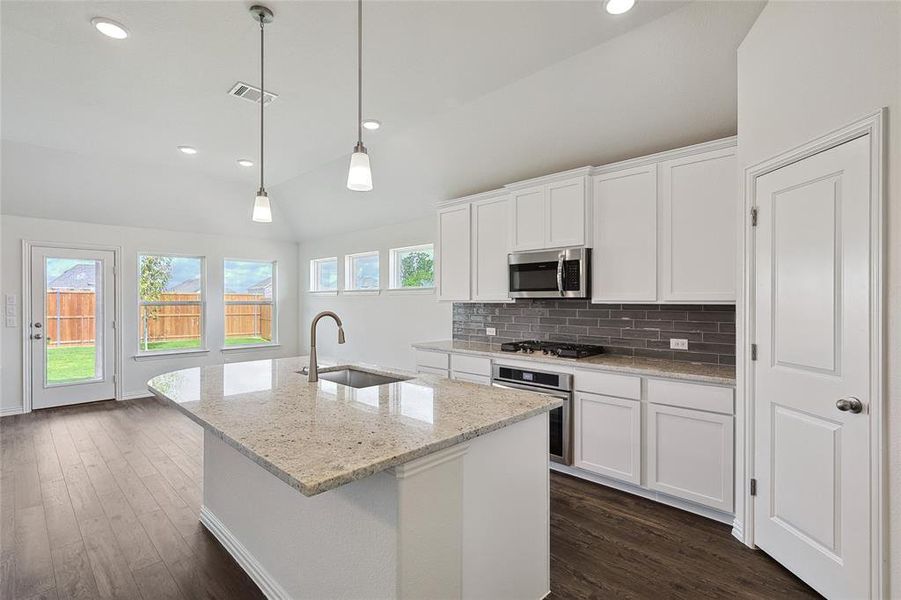 Kitchen with white cabinetry, hanging light fixtures, dark hardwood / wood-style flooring, stainless steel appliances, and sink