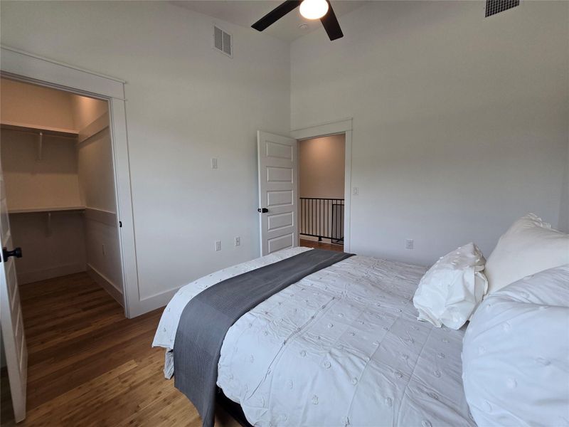 Bedroom with wood finished floors, a high ceiling, a spacious closet, and ceiling fan