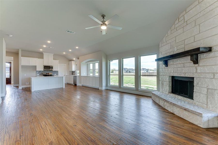 Unfurnished living room with a fireplace, wood-type flooring, ceiling fan, and lofted ceiling