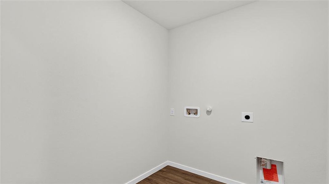 Dedicated utility space featuring light-toned walls, wood-finish flooring, and white baseboards
