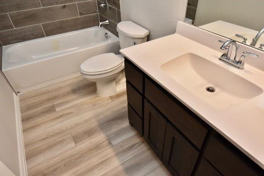 Full bathroom with vanity, wood finished floors, and shower / tub combination Full bathroom with vanity, wood finished floors, and shower / tub combination