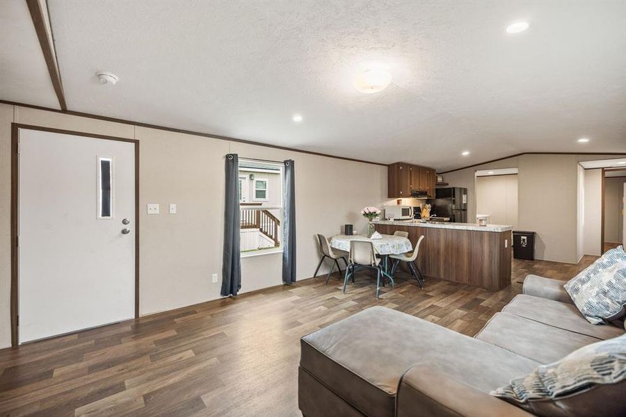 Open-concept living area with wood-finish flooring, recessed lighting, and a neutral color palette Open-concept living area with wood-finish flooring, recessed lighting, and a neutral color palette
