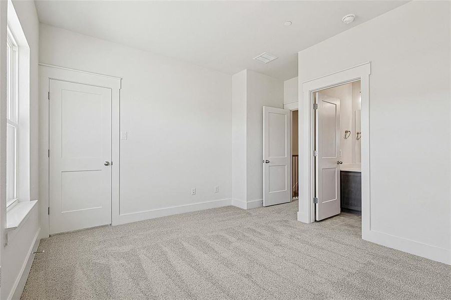 Unfurnished bedroom with light carpet and ensuite bath