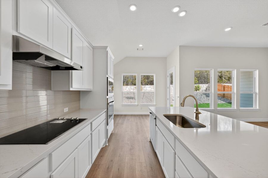 Kitchen with white cabinetry, light wood-style floors, light stone counters, stainless steel appliances, and recessed lighting Kitchen with white cabinetry, light wood-style floors, light stone counters, stainless steel appliances, and recessed lighting