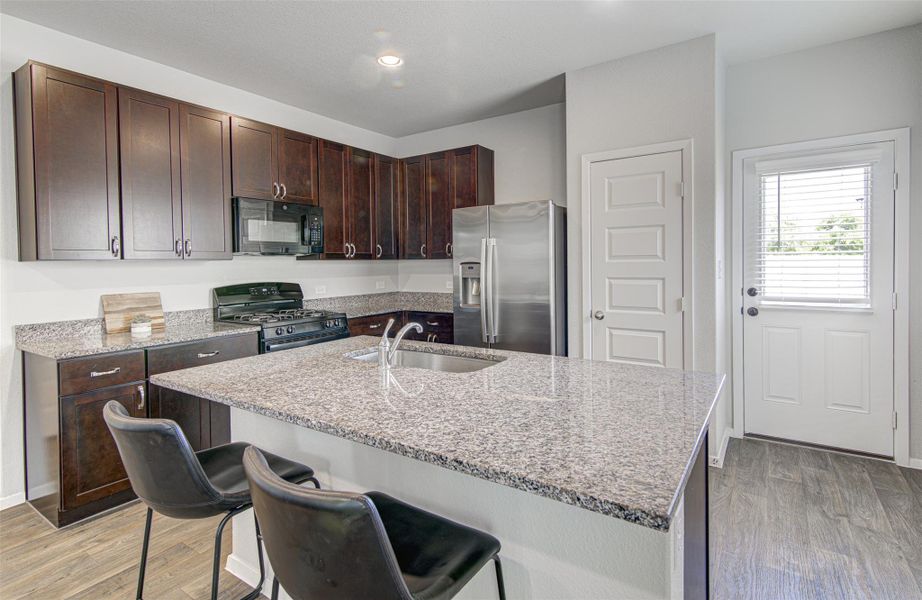 A well-appointed kitchen features a central island, granite countertops, and rich cabinetry. A well-appointed kitchen features a central island, granite countertops, and rich cabinetry.