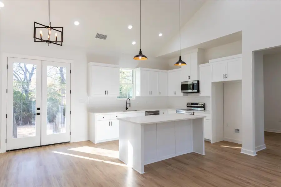 Step into this stunning home with a kitchen that showcases French doors, stylish backsplash, and modern stainless-steel accents.