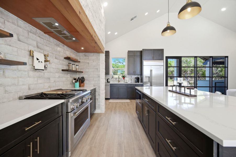 High vaulted ceilings and a massive central island anchor this modern culinary space.