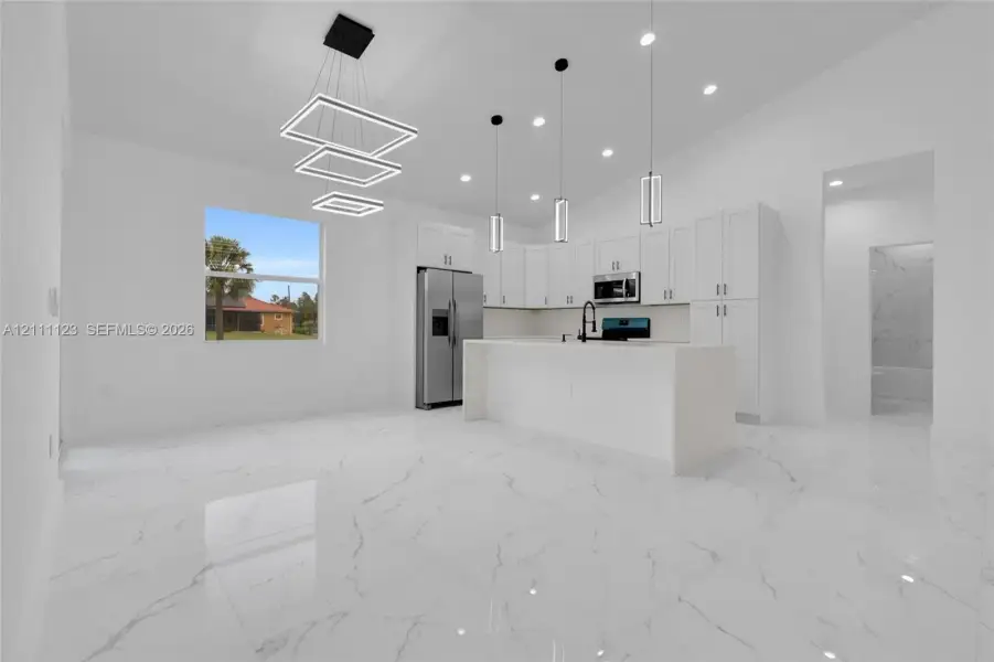 Dining area with modern light fixture, open to the kitchen island.