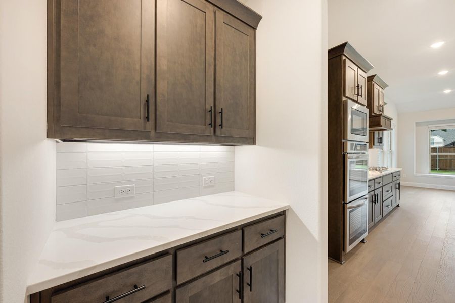 Kitchen with dark brown cabinets, white quartz countertops, tile backsplash, and stainless steel appliances visible in background. Kitchen with dark brown cabinets, white quartz countertops, tile backsplash, and stainless steel appliances visible in background.