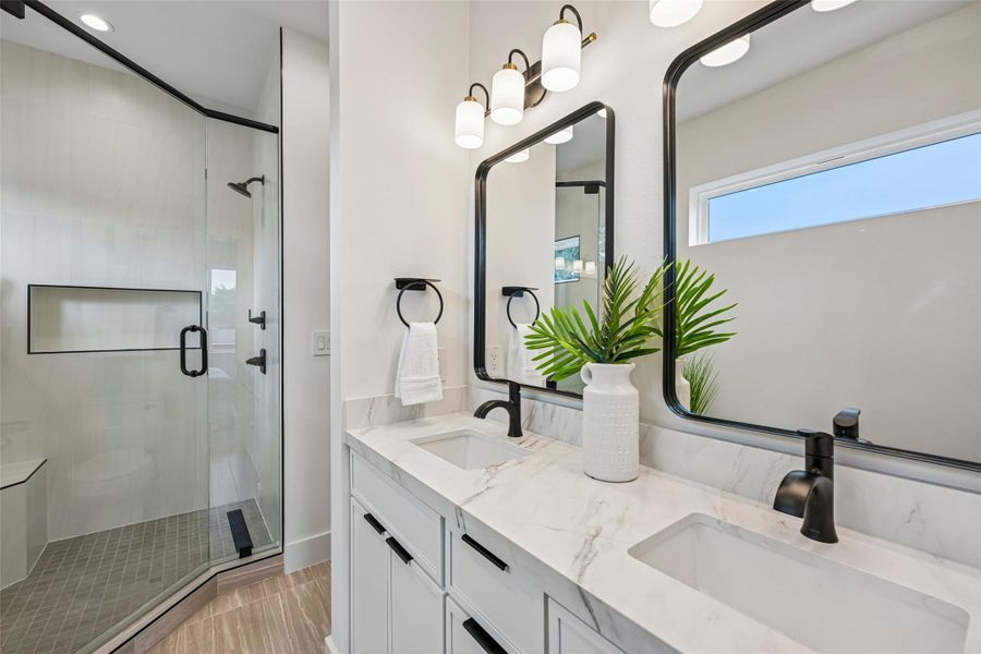 Dual vanities with sleek black fixtures and a frameless glass shower create a modern sanctuary.