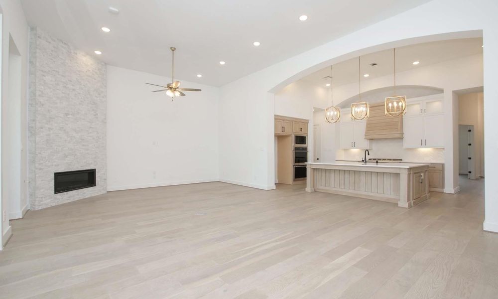 Unfurnished living room with a ceiling fan, recessed lighting, light wood-type flooring, a fireplace, and arched walkways