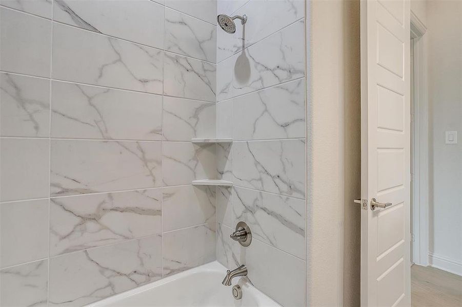 Bathroom with hardwood / wood-style flooring and tiled shower / bath combo