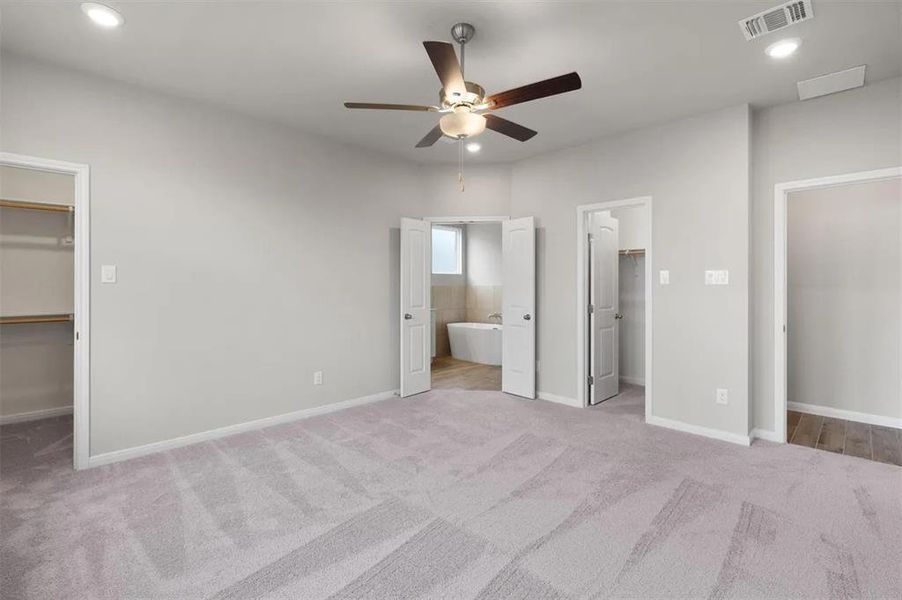 A spacious primary bedroom features soft carpeting and direct access to a private bathroom.