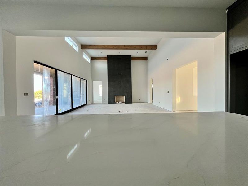 Unfurnished living room featuring beamed ceiling and a large fireplace