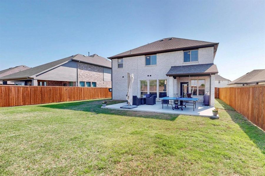 Back of house featuring brick siding, a fenced backyard, a patio, and an outdoor living space
