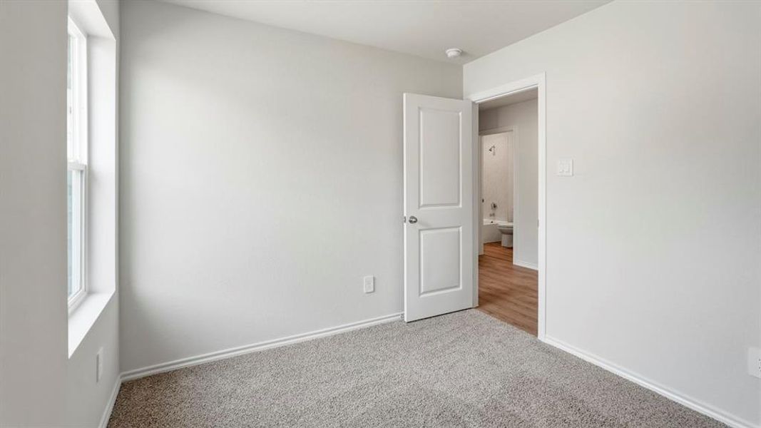 Unfurnished room featuring light carpet and baseboards