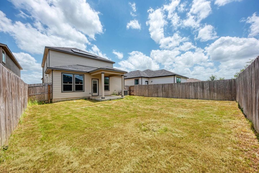 A spacious backyard provides ample green space, secured by sturdy wood fencing, perfect for outdoor activities.
