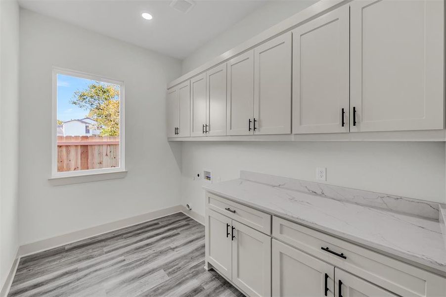 Laundry room with hookup for a washing machine, light wood-style flooring, recessed lighting, and cabinet space