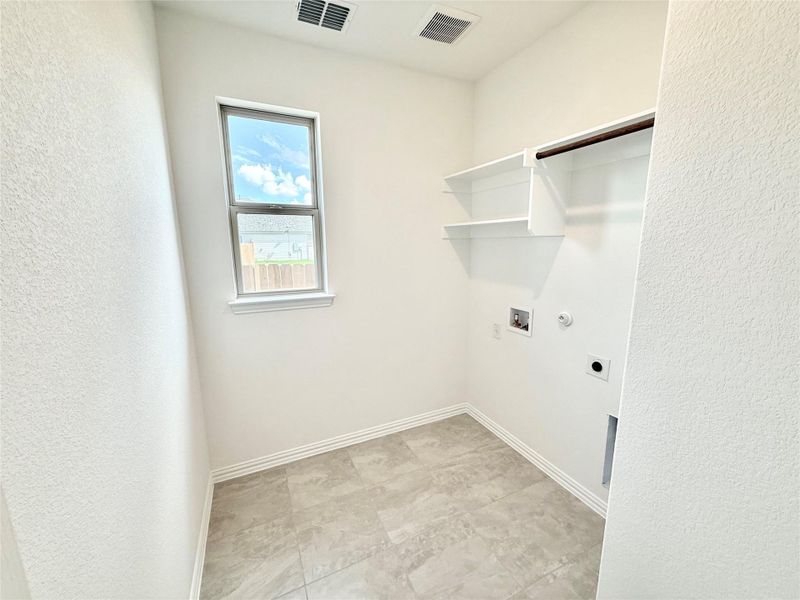 Laundry area with hookup for a gas dryer, a textured wall, hookup for a washing machine, and electric dryer hookup Laundry area with hookup for a gas dryer, a textured wall, hookup for a washing machine, and electric dryer hookup