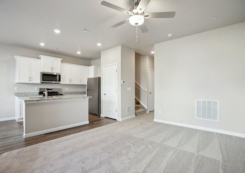 The kitchen has stainless steel appliances and plank flooring and is open to the family room.