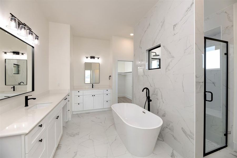 Bathroom with a freestanding tub, a sink, two vanities, a marble finish shower, and marble finish floor