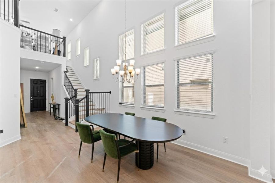 Dining area featuring stairway, a chandelier, light wood-type flooring, a high ceiling, and recessed lighting Dining area featuring stairway, a chandelier, light wood-type flooring, a high ceiling, and recessed lighting