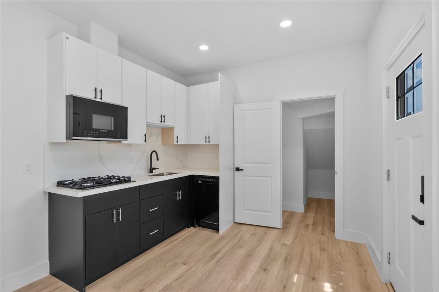 Sleek modern kitchen featuring custom cabinetry, quartz surfaces and striking designer contrasts on the first floor Sleek modern kitchen featuring custom cabinetry, quartz surfaces and striking designer contrasts on the first floor
