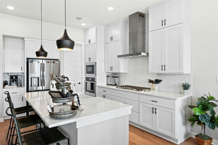 Kitchen with a breakfast bar area, an island with porcelain farmers sink, light wood finished floors, and light stone countertops