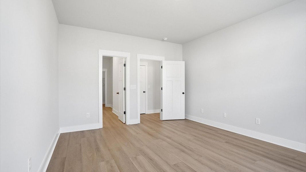 Elegant primary suite with hardwood flooring and superior natural light in this accomplished DRB Homes design Elegant primary suite with hardwood flooring and superior natural light in this accomplished DRB Homes design