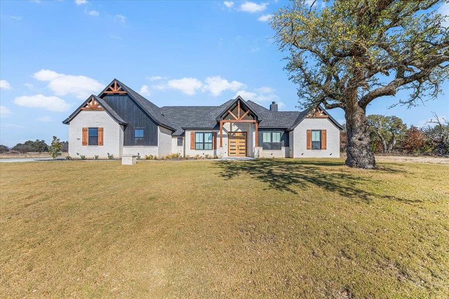 Facing front of home with beautiful large oak tree.