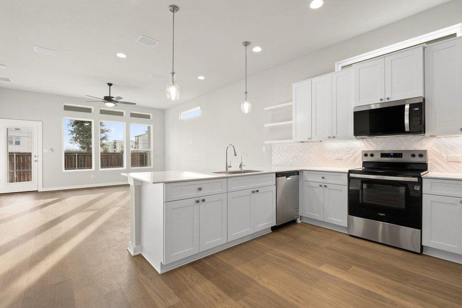 Kitchen featuring stainless steel appliances, open shelves, backsplash, hanging light fixtures, and white cabinets