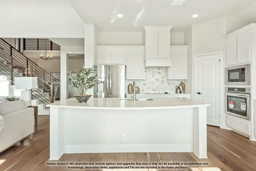 White kitchen with large island, stainless steel appliances, marble backsplash, and hardwood floors open to living area White kitchen with large island, stainless steel appliances, marble backsplash, and hardwood floors open to living area